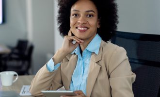 heureuse-femme-d-affaires-afro-americaine-travaillant-sur-un-pave-tactile au-bureau